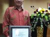 Kadis Perdagangan Koperasi dan UKM Kotamobagu Herman Arai saat menerima piagam penghargaan
