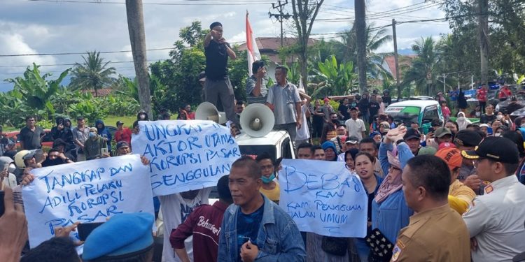 Protes kebijakan Wali Kota Kotamobagu Tatong Bara datang dari para pedagang kaki lima bersama, aktifis LSM dan elemen masyarakat Kota Kotamobagu. Mereka menggelar aksi demo di Kantor DPRD dan Kantor Kejaksaan Negeri Kotamobagu Senin 8 Agustus 2022. Aksi itu untuk memprotes kebijakan Wali Kota Tatong Bara yang dinilai merugikan masyarakat dan pedagang. Aksi demo ratusan massa itu, diawali di depan Kantor Kejaksaan. Kedatangan mereka untuk memberikan dukungan sekaligus mendesak agar pihak Kejaksaan menseriusi kasus dugaan Korupsi Pasar Genggulang yang sedang ditangani. Kasus korupsi Pasar Genggulang telah menetapkan dua orang sebagai tersangka. Salah satu peserta aksi, dari elemen masyarakat Irawan Damopolii mengatakan, aksi yang digelar tersebut bertujuan untuk menyampaikan dukungan sekaligus meminta agar Kejaksaan serius. "Aksi ini sebagai wujud dukungan kami, agar Kejaksaan seriusi dalam penanganan kasus korupsi Pasar Genggunlang yang telah menetapkan dua orang sebagai tersangka," kara Irawan. Menurutnya, proyek pembangunan Pasar Genggulang yang menggunakan APBD puluhan miliaran rupiah itu, telah merugikan masyarakat sehingga perlu diseriusi. Selama kurang lebih 30 menit berorasi di depan Kantor Kejaksaan, masa melanjutkan melakukan aksi di depan Kantor DPRD di Jalan Paloko Kinalang. Saat tiba di depan Kantor DPRD sempat terjadi aksi dorong dengan petugas karena massa memaksa masuk. Namun aksi dorong itu tak berlangsung lama karena Ketua DPRD Kotamobagu Meiddy Makalalag langsung menemui massa pendemo dan mempersilahkan masuk. Di hadapan para wakil rakyat, mereka menyampaikan aspirasi, terkait kebijakan Wali Kota Kotamobagu yang menutup akses masuk di Pasar Serasi dan jalan 23 Maret. Penutupan akses ke pasar itu, melibatkan aparat dari TNI POLRI. Sedikitnya ada empat titik akses yang diblokade dan jaga ketat aparat. Penutupan itu, buntut pemindahan sebagian pedagang ke Pasar Genggulang. Menurut mereka, keijakan tersebut justru merugikan para pedagang serta pemilik toko lainnya. “Kebijakan Wali Kota Kotamobagu Tatong Bara yang menutup akses jalan masuk ke pasar Serasi tidak manusiawi dan hanya merugikan masyarakat yang tinggal di kompleks pasar. Begitu juga bagi para pedagang warung makan dan toko penjual bahan bangunan,” kata Ketua salah satu elemen masyarakat Ando Lobud. Ando menegaskan, penutupan beberapa titik masuk ke Pasar Serasi telah melanggar hak asasi manusia sebab banyak warga yang merasa tertekan dan pedagang dirugikan. "Kami sebagai warga yang tinggal di kompleks Pasar Serasi dan Pasar 23 Maret menerima dampak dari penutupan akses masuk. Selain itu, ikut memberikan kerugian bagi para pemilik warung makan, toko, dan kios," katanya. Dibeberapa titik masuk ke Pasar Serasi dan Pasar 23 Maret sejumlah aparat TNI Polri ikut dikerahkan untuk berjaga-jaga. Padahal hanya dalam rangka memindahkan sebagian pedagang ke Pasar Genggulang karena telah menempati badan jalan. "Di Kompleks pasar itu, bukan hanya pedagang kecil saja yang berjualan. Tetapi di sana ada toko, dan warung makan. Selama penutupan jalan, para pemilik warung makan mengalmi kerugian karena tidak ada pembeli," katanya. Ketua LBI Dofie Paat lewat pernyataan sikap menegaskan, menolak penutupan jalan keluar masuk pasar yang dilakukan Pemkot Kotamobagu sejak Kamis (4/8). Menurut Dolfie, penutupan akses ke pasar seperti Daerah Operasi Militer (DOM) dan mencekam. Karena disetiap pos penjagaan ada aparat terkesan di wilayah itu terkesan seperti ada Teroris Pusat perbelanjaan usaha pertokoan,rumah makan, serta transportasi mati total karna tidak bisa masuk.Dan ini telah mengakibatkan pelaku usaha rugi besar. “Selaku Ormas, kami meminta kepada DPRD membuat rekomendasi untuk segera membuka akses,” tegasnya. Ketua DPRD Kotamobagu Meiddy Makalalag berjanji akan turun untuk melihat secara langsung penutupan akses masuk pasar. (*)