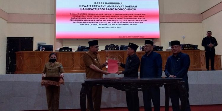 TOTABUAN.CO BOLMONG – Dewan Perwakilan Rakyat Daerah (DPRD) Kabupaten Bolaang Mongondow (Bolmong) mengesahkan Rancangan Peraturan Daerah (Ranperda) tentang Badan Usaha Milik Desa (Bumdes) menjadi Peraturan Daerah (Perda). Pengesahan itu dilakukan lewat Paripurna yang dipimpin Ketua DPRD Welty Komaling dihadiri dua wakil pimpinan DPRD serta para anggota. Rapat paripurna itu juga dihadiri Penjabat Bupati Bolmong Limi Mokodompit, Sekretaris Daerah Tahlis Gallang, para Asisten, pimpinan OPD serta Camat. Menurut Ketua DPRD Bolmong, Ranperda Bumdes yang disahkan menjadi Perda, merupakan produk atau inisiatif DPRD. “Ranperda Bumdes yang disahkan menjadi Perda ini, merupakan Ranperda Inisiatif DPRD,” ujar Welty Senin 5 September 2022. Ranperda Bumdes yang digagas DPRD Bolmong ini, dinilai sangat penting untuk memaksimalkan dalam pengelolaan badan usaha di desa. Selain itu dikatakannya, dalam rangka peningkatan penyelenggaraan pemerintahan desa, pelaksanaan pembangunan desa serta pendapatan masyarakat dan desa, agar pemerintah desa dapat mengoptimalkan sumber daya yang dimiliki sesuai kebutuhan dan potensi desa. Welty menambahkan, hadirnya Perda Bumdes, untuk memberikan kepastian hukum dan tertib dalam pendirian, pengelolaan dan pembubaran Bumdes di Kabupaten Bolmong. “Tujuan pendirian Bumdes untuk melaksanakan kegiatan usaha ekonomi melalui pengelolaan usaha, serta pengembangan investasi dan produktivitas perekonomian, dan potensi di desa,” tambahnya. Penjabat Bupati Bolmong Limi Mokodompit menyampaikan apresiasi atas kerja keras DPRD yang berhasil melahirkan produk hukum tentang Bumdes. Ia menambahkan, DPRD yang memiliki tugas sebagai legislasi telah menunjukan komitmen, dalam mengarahkan, memberikan kepastian hukum terkait pengelolaan Bumdes di desa. Bumdes adalah badan usaha yang bercirikan desa yang akan membantu penyelenggaraan pemerintahan desa dan untuk memenuhi kebutuhan masyarakat desa,” kata Limi. Selain itu, setelah disahkan, Bumdes sudah bisa melakukan kegiatan pelayanan umum melalui penyediaan barang atau jasa serta pemenuhan kebutuhan umum masyarakat desa. Yang bertujuan untuk keuntungan dalam rangka peningkatan pendapatan asli desa untuk melakukan pengembangkan usaha sebesar-besarnya sebagai sumber ekonomi masyarakat. Diketahui, selain telah menetapkan satu Perda inisiatif, DPRD juga telah membahas tigas Ranperda inisiatif lainnya. Yakni Ranperda tentang Haji, Ranperda tentang Kepemudaan dan Ranperda kedudukan protokoler, hak keuangan dan administratif pimpinan dan anggota DPRD. Rapat Paripurna DPRD itu dilakukan penyampaian perubahan Kebijakan Umum Anggaran (KUA) serta Prioritas Plafon Anggaran Sementara (PPAS) APBD Tahun Anggaran 2022. (*)
