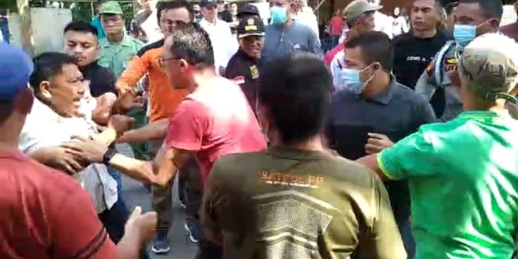 TOTABUAN.CO KOTAMOBAGU – Proyek pemagaran akses jalan masuk Rumah Sakit Umum Daerah Kotamobagu berujung ricuh Jumat 4 November 2022. Akibatnya warga yang menolak proyek pemagaran tersebut terlibat saling dorong dengan petugas dari Satpol PP. Para pekerja proyek pemagaran akses jalan masuk RSUD Kotamobagu itu dihalangi warga dengan membuat garis batas pagar dengan menggunakan alat berat. Namun aksi tersebut dicegat petugas Satpol PP. Aksi saling dorong pun terhindarkan karena warga berupaya menghentikan proses pekerjaan yang sedang berlangsung. Akibatnya, salah satu ibu jatuh pingsan sehingga harus dilarikan ke rumah sakit untuk mendapatkan pertolongan medis. Menurut warga aksi penolakan ini sebagai bentuk protes terhadap kebijakan pemerintah Kotamobagu yang melakukan pemagaran jalan masuk RSUD Kotamobagu setinggi dua meter perlu dikaji kembali. Sebab akan berdampak pada usaha warga seperti warung, kios dan rumah makan tempat mereka mencari nafkah sehari-hari. “Jalan ini milik publik semua orang punya hak menggunakan jalan ini baik pejalan kaki maupun kendaraan. Jangan sampai pemagaran ini merampas hak masyarakat. Pemerintah harus arif dan bijaksana. Ini kesalahan prosedural apalagi dalam pekerjaan ini melibatkan TNI," ujar Rofinus Talulendang. Penolakan itu lantaran Pemkot Kotamobagu dinilai melanggar kesepakatan awal yang notabene tidak ada pemagaran ruas jalan. Kendat demikian, pemerintah punya alasan terkait pemagaran tersebut. Selain untuk meningkatkan akreditas rumah sakit rujukan di Bolaang Mongondow Raya, pihak rumah sakit juga telah melakukan sosialisasi kepada warga sekitar. Bahkan akses tetap diberikan kiri dan kanan selebar 3,5 meter. "Dasar pemagaran ini sesuai dengan Permenkes Nomor 14 Tahun 2021 terkait akses jalan masuk rumah sakit. Kami juga jauh sebelumnya telah mensosialisasikan terkait pemagaran ini. Bahkan tetap akan berikan jalan. Pemagaran ini dilakukan untuk akreditas rumah sakit karena rumah sakit Kotamobagu merupakan rumah sakit rujukan di BMR," ujar Kabag Umum dan Adminitrasi RSUD Kotamobagu Topan Simbala. Kendati mendapat penolakan dari warga, proses pekerjaan tetap berlangsung. Diketahui pada pelaksana pekerjaan itu dilakukan lewat Karya Bhakti oleh Kodim 1303 Bolaang Mongondow dengan total anggaran senilai 900 juta rupiah. (*)