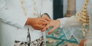 TOTABUAN.CO BOLMONG – WM (41) terpaksa harus melaporkan suaminya FP ke Badan Kepegawain Pendidikan dan Pelatihan (BKPP) Kabupaten Bolaang Mongondow (Bolmong). FP diketahui telah menikah secara diam-diam tanpa sepengetahuan WM sebagai istri sahnya. Pernikahan itu pun sudah dilakukan sejak 2019 silam. Kisah pernikahan siri oknum pejabat yang sehari-hari bertugas di Kantor Sekretariat DPRD Bolmong itu, baru terkuak Januari 2023.    Kepada wartawan, WM menceritakan kisah pilunya sambil menunjukan bukti surat pernyataan pernikahan FP. Dengan mata berkaca-kaca sambil menunjukan bukti surat pernikahan, WM menceritakan ihwal kasus itu terkuak. Ia mengaku tak menyangka suaminya FP sudah menikah secara siri di Gorontalo. Berdasarkan bukti surat, FP menikah Kamis 17 Oktober 2019 dengan HP yang diketahui sebagai ASN di Pemkot Kotamobagu, ucap WM yang didampingi kakaknya. Ia sedih karena sudah tiga tahun pasca pernikahan siri dengan HP, namun baru diketahui Januari 2023. Atas kejadian tersebut, Ia mengaku sudah mengadukan langsung ke Bupati terkait tindak pernikahan suaminya tanpa izin. WM mengatakan, wanita yang dinikahinya itu merupakan perempuan yang sudah lama menjadi simpanannya. Perempuan tersebut merupakan ASN yang bertugas di Pemkot Kotamobagu. Dalam keteranganya, MW mengaku sudah  menikah dengan suaminya 20 tahun silam hingga dikaruniai dua orang anak. Sejak menjadi ASN hingga dipercayakan menjadi kepala bagian, WM terus mendukungnya dalam tugas. Namun belakangan FP punya niat lain. Termasuk berniat mengincar harta peninggalan orangtuanya. “Sertifikat rumah yang disimpan dicuri. Begitu juga BPKB mobil milik orang tua saya digadaikan. Ternyata uang hasil penjualan rumah dan BPKB hanya untuk membiayai wanita yang disimpan selama ini,” cerita WM. Ia saat ini sudah tidak tahan lagi mempertahankan rumah tangganya akibat orang ketiga. Sikap WM saat ini sudah bulat untuk menggugat cerai di Kantor Pengadilan Agama Lolak, bahkan akan melaporkan kasus ini ke Polisi. “Semua keluarga mendukung langkah saya untuk menggugat cerai. Dan meminta kepada Bupati untuk memberikan sanksi jika perlu dipecat,” pintanya. Dengan mengantongi bukti-bukti, WM juga akan melaporkan HP ke BKPP Pemkot Kotamobagu.                                                        *** Nikah siri menurut kamus besar bahasa Indonesia (KBBI) adalah pernikahan yang hanya disaksikan oleh seorang modin dan saksi, tidak melalui Kantor Urusan Agama (KUA). Sebagai abdi negara, seorang ASN dalam melaksanakan pernikahan harus berpedoman pada sejumlah peraturan yang ada. Peraturan bagi PNS yang nikah siri salah satu pedoman bagi PNS yang akan melangsungkan pernikahan adalah Peraturan Pemerintah (PP) Nomor 45 Tahun 1990 tentang perubahan atas PP Nomor 10 Tahun 1983 tentang Izin perkawinan dan perceraian bagi PNS. Dalam peraturan ini, PNS dilarang untuk melakukan nikah siri. Seluruh PNS diwajibkan untuk melaporkan pernikahannya kepada pejabat yang berwenang. Hal ini mengacu pada Pasal 2 Ayat 1 yang berbunyi, “PNS yang melangsungkan perkawinan pertama, wajib memberitahukannya secara tertulis kepada pejabat melalui saluran hierarki dalam waktu selambat-lambatnya satu tahun setelah perkawinan itu dilangsungkan.” Ketentuan ini juga berlaku untuk PNS yang telah menjadi duda atau janda dan telah melangsungkan perkawinan lagi. Dalam peraturan ini, nikah siri disamakan dengan pasangan yang hidup bersama tanpa ikatan sah. Pasal 14 PP Nomor 45 Tahun 1990 berbunyi, “PNS dilarang hidup bersama dengan wanita yang bukan istrinya atau dengan pria yang bukan suaminya sebagai suami istri tanpa ikatan perkawinan yang sah. Yang dimaksud dengan hidup bersama dalam pasal ini adalah melakukan hubungan sebagai suami istri di luar ikatan perkawinan yang sah yang seolah-olah merupakan suatu rumah tangga. Hal ini bertentangan dengan UU Nomor 1 Tahun 1974 tentang Perkawinan yang diubah dengan UU Nomor 16 Tahun 2019. Dalam Pasal 2 UU ini, perkawinan dianggap sah jika dilakukan menurut hukum agama dan kepercayaan, serta dicatat menurut peraturan perundang-undangan yang berlaku. Nikah siri pun dinilai tidak memenuhi unsur-unsur pernikahan yang sah menurut terminologi undang-undang ini. Sanksi bagi PNS yang Nikah Siri Akibat melakukan nikah siri, seorang PNS akan dijatuhi salah satu hukuman disiplin berat. Dalam Pasal 8 Ayat 4 PP Nomor 94 Tahun 2021 tentang Peraturan Disiplin PNS, terdapat tiga jenis hukuman disiplin berat, yaitu: penurunan jabatan setingkat lebih rendah selama 12 bulan, pembebasan dari jabatannya menjadi jabatan pelaksana selama 12 bulan, dan pemberhentian dengan hormat tidak atas permintaan sendiri sebagai PNS. (*) 