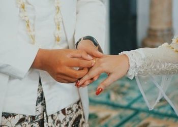 TOTABUAN.CO BOLMONG – WM (41) terpaksa harus melaporkan suaminya FP ke Badan Kepegawain Pendidikan dan Pelatihan (BKPP) Kabupaten Bolaang Mongondow (Bolmong). FP diketahui telah menikah secara diam-diam tanpa sepengetahuan WM sebagai istri sahnya. Pernikahan itu pun sudah dilakukan sejak 2019 silam. Kisah pernikahan siri oknum pejabat yang sehari-hari bertugas di Kantor Sekretariat DPRD Bolmong itu, baru terkuak Januari 2023.    Kepada wartawan, WM menceritakan kisah pilunya sambil menunjukan bukti surat pernyataan pernikahan FP. Dengan mata berkaca-kaca sambil menunjukan bukti surat pernikahan, WM menceritakan ihwal kasus itu terkuak. Ia mengaku tak menyangka suaminya FP sudah menikah secara siri di Gorontalo. Berdasarkan bukti surat, FP menikah Kamis 17 Oktober 2019 dengan HP yang diketahui sebagai ASN di Pemkot Kotamobagu, ucap WM yang didampingi kakaknya. Ia sedih karena sudah tiga tahun pasca pernikahan siri dengan HP, namun baru diketahui Januari 2023. Atas kejadian tersebut, Ia mengaku sudah mengadukan langsung ke Bupati terkait tindak pernikahan suaminya tanpa izin. WM mengatakan, wanita yang dinikahinya itu merupakan perempuan yang sudah lama menjadi simpanannya. Perempuan tersebut merupakan ASN yang bertugas di Pemkot Kotamobagu. Dalam keteranganya, MW mengaku sudah  menikah dengan suaminya 20 tahun silam hingga dikaruniai dua orang anak. Sejak menjadi ASN hingga dipercayakan menjadi kepala bagian, WM terus mendukungnya dalam tugas. Namun belakangan FP punya niat lain. Termasuk berniat mengincar harta peninggalan orangtuanya. “Sertifikat rumah yang disimpan dicuri. Begitu juga BPKB mobil milik orang tua saya digadaikan. Ternyata uang hasil penjualan rumah dan BPKB hanya untuk membiayai wanita yang disimpan selama ini,” cerita WM. Ia saat ini sudah tidak tahan lagi mempertahankan rumah tangganya akibat orang ketiga. Sikap WM saat ini sudah bulat untuk menggugat cerai di Kantor Pengadilan Agama Lolak, bahkan akan melaporkan kasus ini ke Polisi. “Semua keluarga mendukung langkah saya untuk menggugat cerai. Dan meminta kepada Bupati untuk memberikan sanksi jika perlu dipecat,” pintanya. Dengan mengantongi bukti-bukti, WM juga akan melaporkan HP ke BKPP Pemkot Kotamobagu.                                                        *** Nikah siri menurut kamus besar bahasa Indonesia (KBBI) adalah pernikahan yang hanya disaksikan oleh seorang modin dan saksi, tidak melalui Kantor Urusan Agama (KUA). Sebagai abdi negara, seorang ASN dalam melaksanakan pernikahan harus berpedoman pada sejumlah peraturan yang ada. Peraturan bagi PNS yang nikah siri salah satu pedoman bagi PNS yang akan melangsungkan pernikahan adalah Peraturan Pemerintah (PP) Nomor 45 Tahun 1990 tentang perubahan atas PP Nomor 10 Tahun 1983 tentang Izin perkawinan dan perceraian bagi PNS. Dalam peraturan ini, PNS dilarang untuk melakukan nikah siri. Seluruh PNS diwajibkan untuk melaporkan pernikahannya kepada pejabat yang berwenang. Hal ini mengacu pada Pasal 2 Ayat 1 yang berbunyi, “PNS yang melangsungkan perkawinan pertama, wajib memberitahukannya secara tertulis kepada pejabat melalui saluran hierarki dalam waktu selambat-lambatnya satu tahun setelah perkawinan itu dilangsungkan.” Ketentuan ini juga berlaku untuk PNS yang telah menjadi duda atau janda dan telah melangsungkan perkawinan lagi. Dalam peraturan ini, nikah siri disamakan dengan pasangan yang hidup bersama tanpa ikatan sah. Pasal 14 PP Nomor 45 Tahun 1990 berbunyi, “PNS dilarang hidup bersama dengan wanita yang bukan istrinya atau dengan pria yang bukan suaminya sebagai suami istri tanpa ikatan perkawinan yang sah. Yang dimaksud dengan hidup bersama dalam pasal ini adalah melakukan hubungan sebagai suami istri di luar ikatan perkawinan yang sah yang seolah-olah merupakan suatu rumah tangga. Hal ini bertentangan dengan UU Nomor 1 Tahun 1974 tentang Perkawinan yang diubah dengan UU Nomor 16 Tahun 2019. Dalam Pasal 2 UU ini, perkawinan dianggap sah jika dilakukan menurut hukum agama dan kepercayaan, serta dicatat menurut peraturan perundang-undangan yang berlaku. Nikah siri pun dinilai tidak memenuhi unsur-unsur pernikahan yang sah menurut terminologi undang-undang ini. Sanksi bagi PNS yang Nikah Siri Akibat melakukan nikah siri, seorang PNS akan dijatuhi salah satu hukuman disiplin berat. Dalam Pasal 8 Ayat 4 PP Nomor 94 Tahun 2021 tentang Peraturan Disiplin PNS, terdapat tiga jenis hukuman disiplin berat, yaitu: penurunan jabatan setingkat lebih rendah selama 12 bulan, pembebasan dari jabatannya menjadi jabatan pelaksana selama 12 bulan, dan pemberhentian dengan hormat tidak atas permintaan sendiri sebagai PNS. (*) 