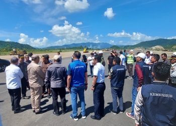 TOTABUAN.CO BOLMONG – Proyek pembangunan Bandar Udara (Bandara) Loloda Mokoagow di Kabupaten Bolaang Mongondow (Bolmong) terus dipacu. Panjang runway yang sedang dibangun sepanjang 1.600 meter yang kini sudah tahap pengaspalan. Kendati demikian, masih terkendala Bukit setinggi 87 meter. Bukti yang berada di Tuyat itu nantinya akan mengganggu proses landing maupun take off pesawat. Hal itu disampaikan Kepala Bandara Naha - Bolmong Dwi Ariyanto saat kunjungan tim dari Kejagung saat memantau progres pengerjaan proyek Bandara pekan lalu. “Masih terdapat kendala saat akan beroperasi nanti. Salah satunya bukit yang ada di Desa Tuyat yang mencapai ketinggian 87 meter lebih,” ucap Dwi di hadapan tim dari Kejagung. Dalam kunjungan itu tim Kejagung juga didampingi Pj Bupati Bolmong Limi Mokodompit, Kejari Kotamobagu Elwin Agustian Khahar, Kepala bandara Naha-Bolmong Dwi Ariyanto serta sejumlah OPD dan pimpinan proyek. Dwi menjelaskan, terdapat kelebihan tinggi bukit yang masih menjadi kendala saat Take Off atau Landing pesawat. Kalu pun Landing atau pun Take Off pesat hanya boleh arah laut karena terkendala bukit Tuyat. Bukit tersebut sudah berada di luar area Bandara sehingga tidak masuk dalam penganggaran. Padahal target percepatan proyek tersebut hingga Maret tahun 2024. “Ini yang masih kita pikirkan. Masih ada waktu untuk proses pemangkasan. Sebab bukit tersebut sudah berada di luar kompleks Bandara,” kata Dwi. Berdasarkan ketinggian bukit, Dwi mengatakan, perlu pemangkasan kurang lebih hampir 50 meter. Kepala Dinas Perhubungan Bolmong Sugiarto Banteng mengatakan, sudah berkoordinasi menyangkut pemangkasan bukit tersebut. Namun belakangan diketahui bukit tersebut masuk kawasan hutan lindung. “Tinggal kita akan berkoordinasi dengan KPH untuk meminta menurunkan status hutan. Perintah dari tim Kejagung juga begitu. Kerja saja dulu nanti penyelesaian status berjalan bersamaan karena mengejar target proses pembangunan,” kata Sugi. Bukit Tuyat saat ini sudah mulai diduduki petani untuk menanam kelapa. Meski demikian pihak BPN tidak mengeluarkan sertifikat karena status tanah tersebut merupakan hutan lindung. Diketahui Kementerian Perhubungan (Kemenhub) menyiapkan anggaran lebih dari Rp 1 triliun untuk pembangunan 7 Bandara baru di tahun 2023. Ketujuh bandara tersebut antara lain Bandara Banggai Laut, Bandara Pahowato, Bandara Bolaang Mongondow, Bandara Sobaham, Bandara Singkawang, Bandara Mandailing Natal, dan Bandara Siboru Fakfak. Pembangunan bandara Bolmong ini merupakan salah satu prioritas dari Presiden RI Joko Widodo. Target bandara Bolmong akan beroperasi tahap 1 tahun 2024. Dengan panjang runway 1600 meter. Digenjotnya proses pembangunan karena direncanakan peresmian Bandara akan dilakukan Presiden Joko Widodo pada April 2024 mendatang. (*)